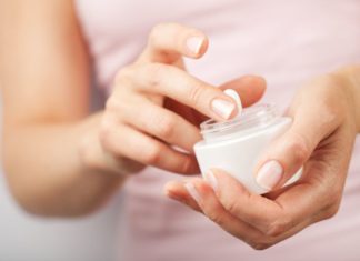 Woman holds a small jar of lotion.