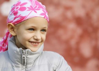 A pale little girl wearing a winter goat with a pink scarf over her head.