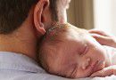 Father At Home With Sleeping Newborn Baby Daughter