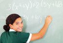 smiling student writing mathematics on the blackboard