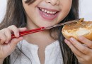 Girl spreads peanut butter on bread